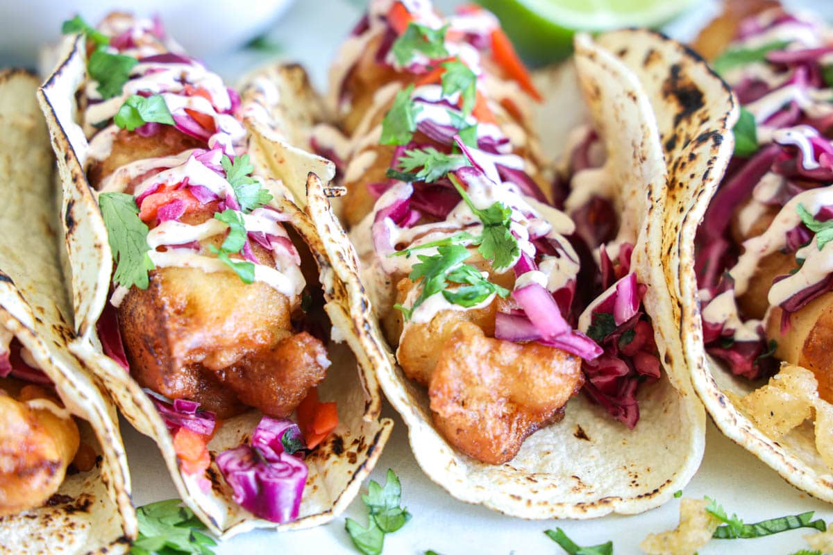 horizontal image of fish tacos with toppings