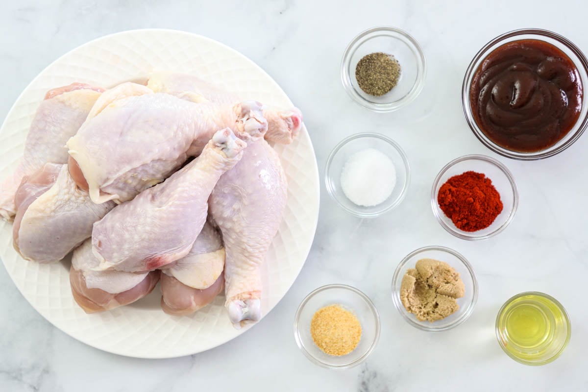 Ingredients for Air Fryer Chicken Legs, including chicken drumsticks, paprika, brown sugar, garlic powder, oil, BBQ sauce, salt and pepper