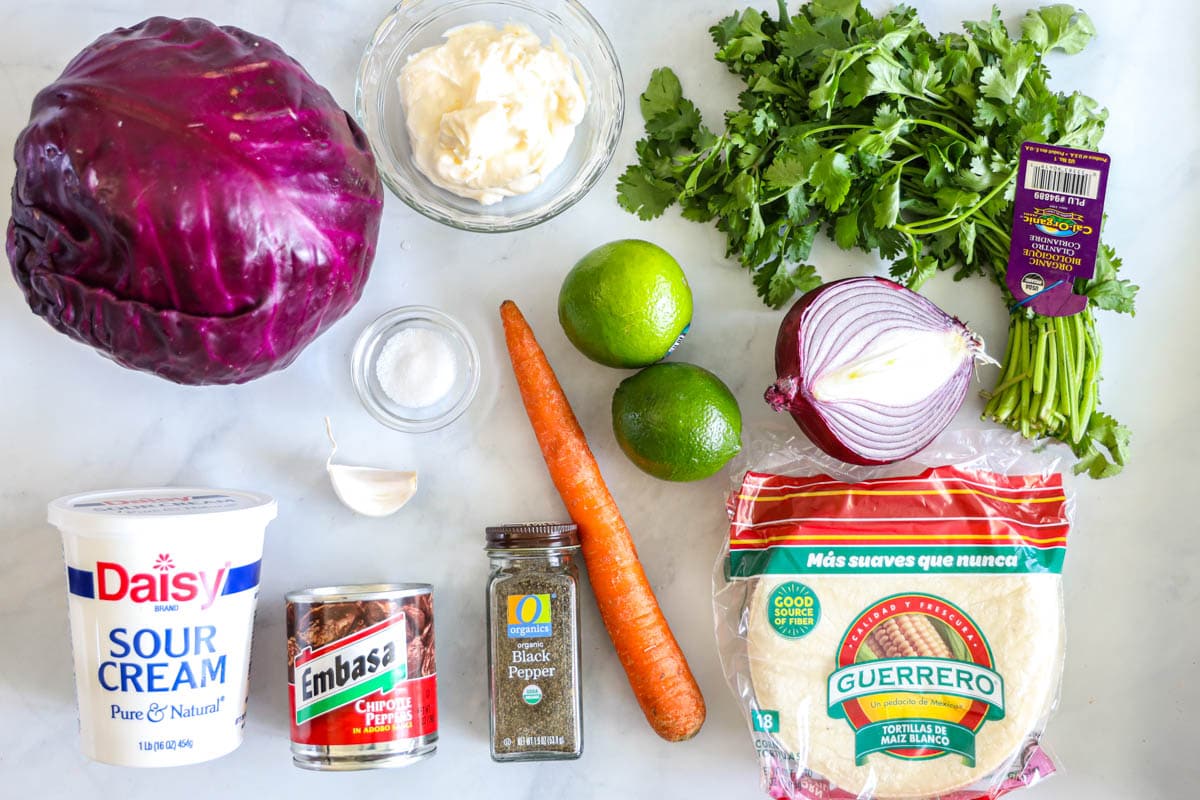 overhead image of ingredients for fish tacos including cabbage slaw, and baja cream sauce