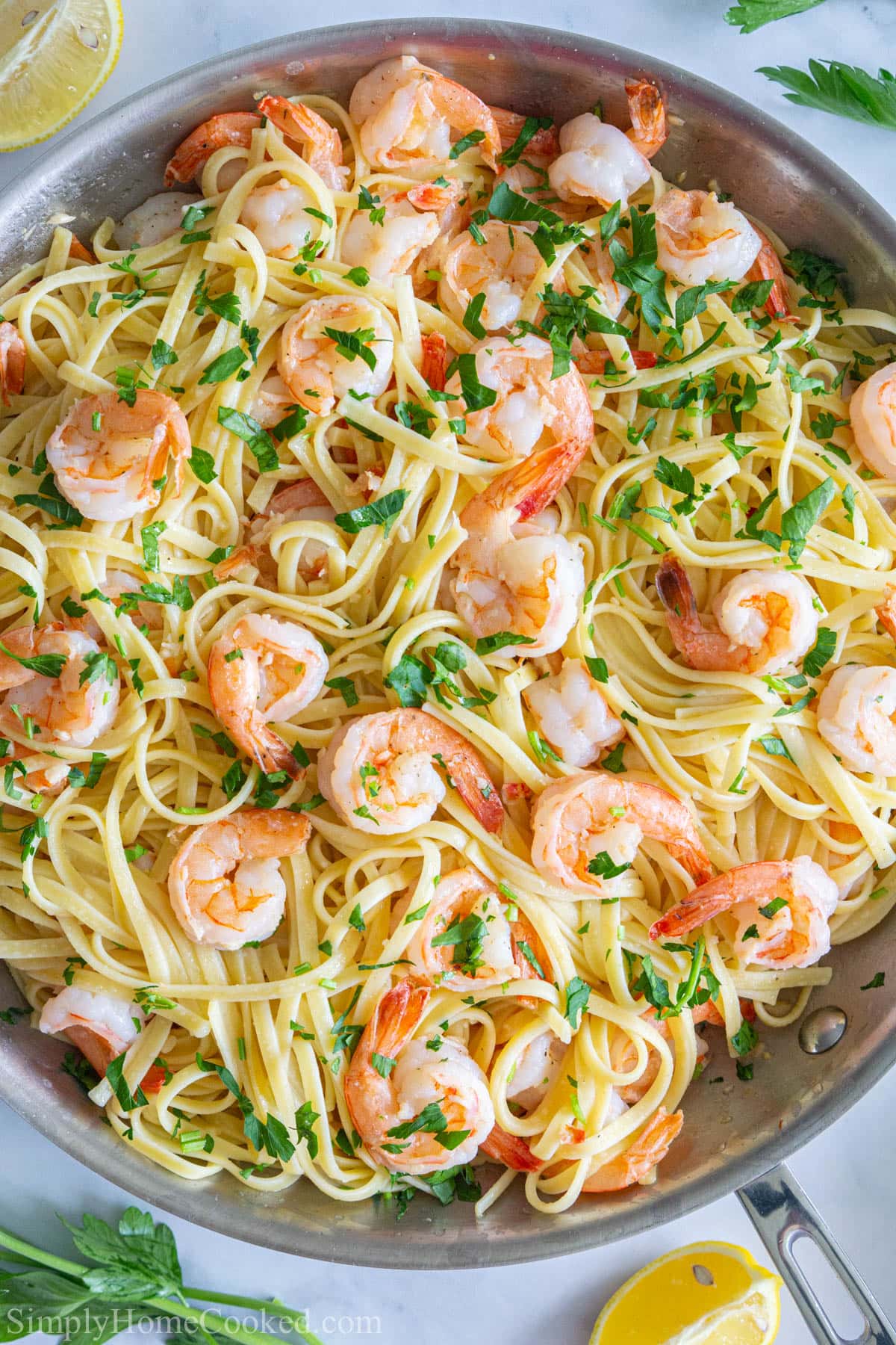 overhead image of shrimps, linguine, and lemon in a skillet