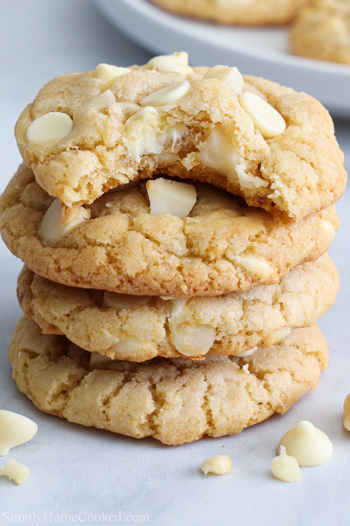 Vertical image of a stack of White Chocolate Macadamia Nut Cookies, one missing a bite.