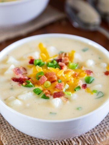 Vertical image of a bowl of Baked Potato Soup with toppings.