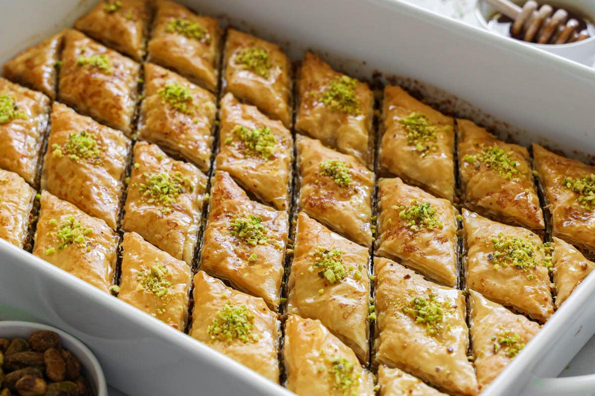 Baking dish of Baklava, slices and garnished with ground pistachios.