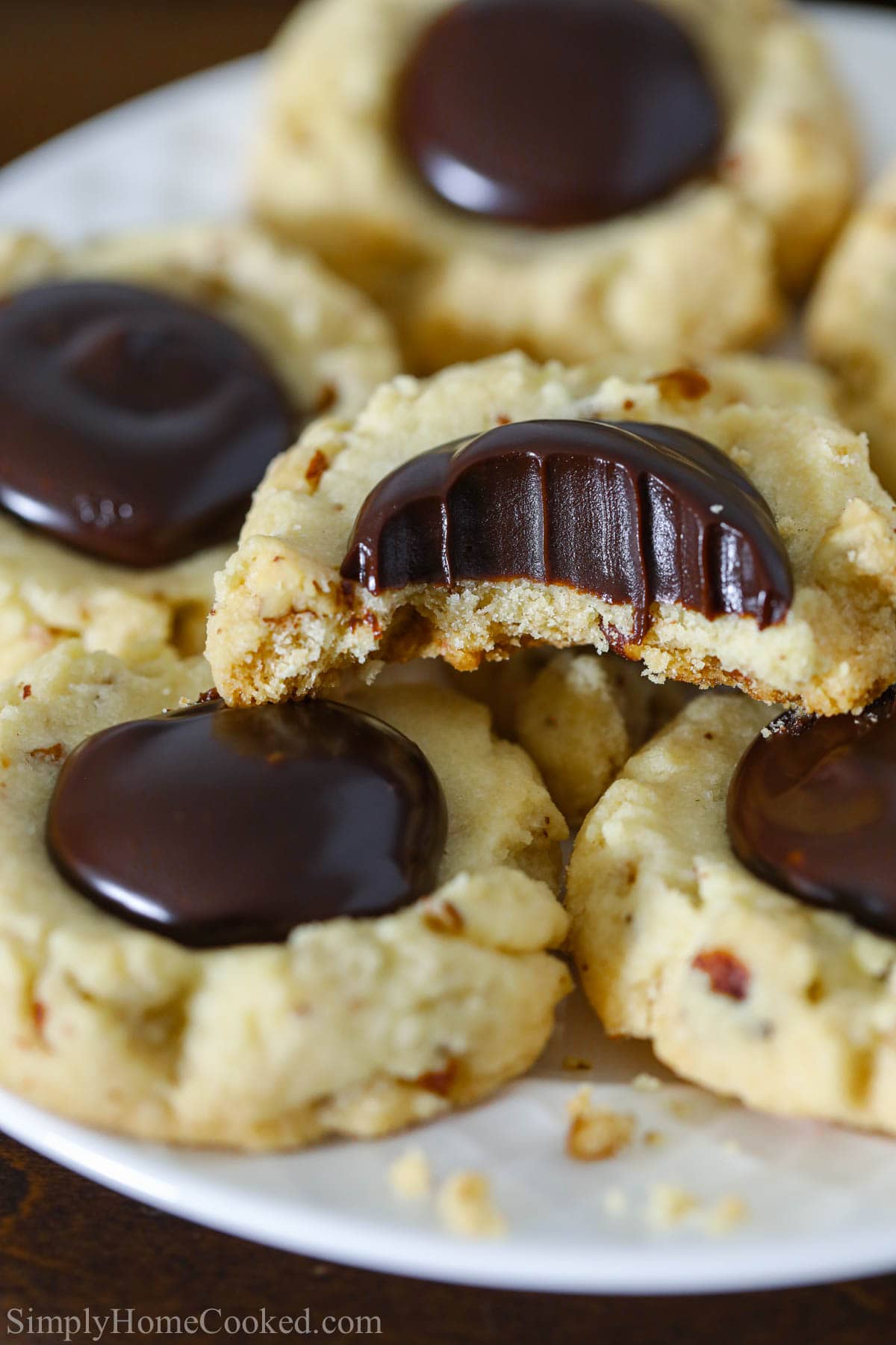 Vertical image of Chocolate Thumbprint Cookies stacked, and a close up on one missing a bite