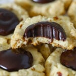 Vertical image of Chocolate Thumbprint Cookies lined up on a pan, and a close up on one missing a bite