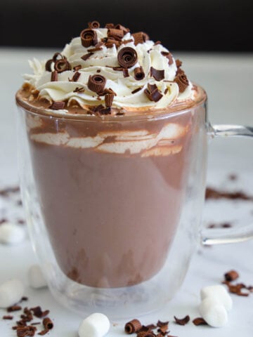 Vertical image of Hot Chocolate in a glass mug with whipped cream and chocolate shavings on top