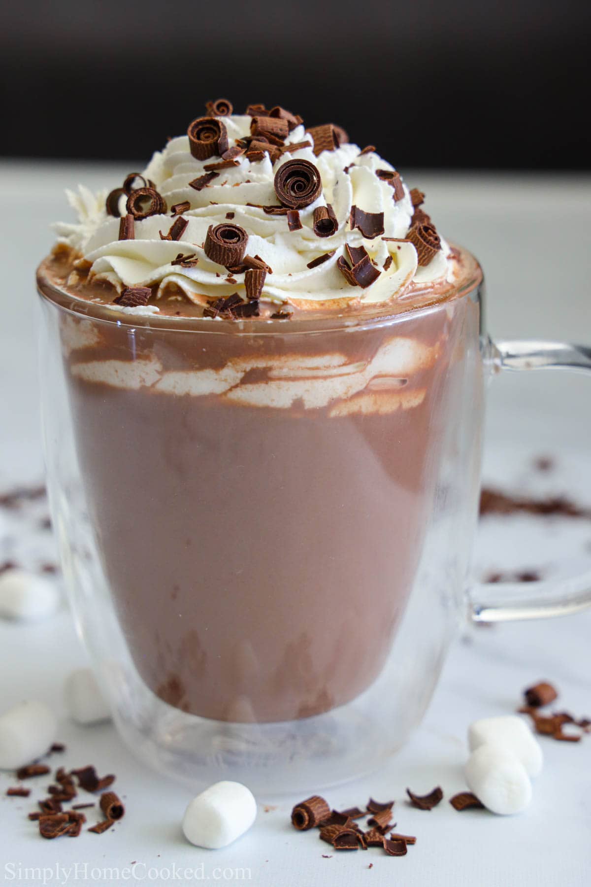 Vertical image of Hot Chocolate in a glass mug with whipped cream and chocolate shavings on top