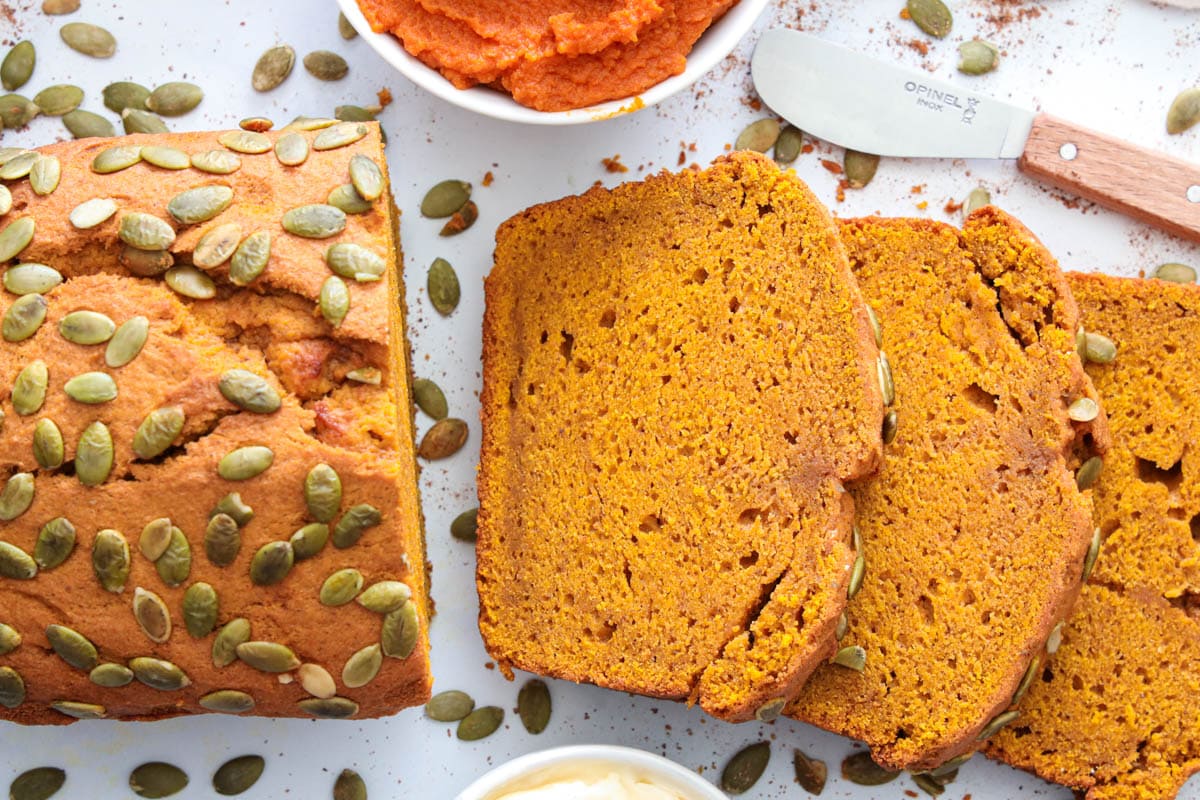 Horizontal image of Pumpkin Bread, sliced and near butter and pumpkin puree