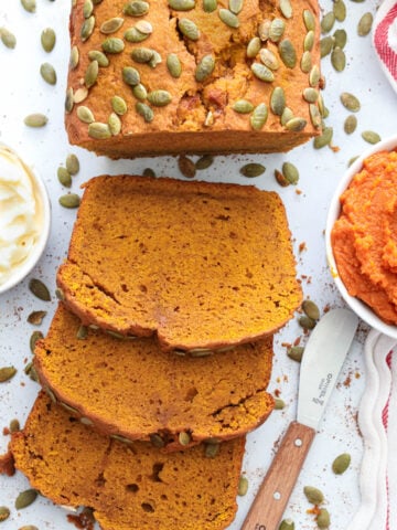 Vertical image of Pumpkin Bread, sliced and near butter and pumpkin puree