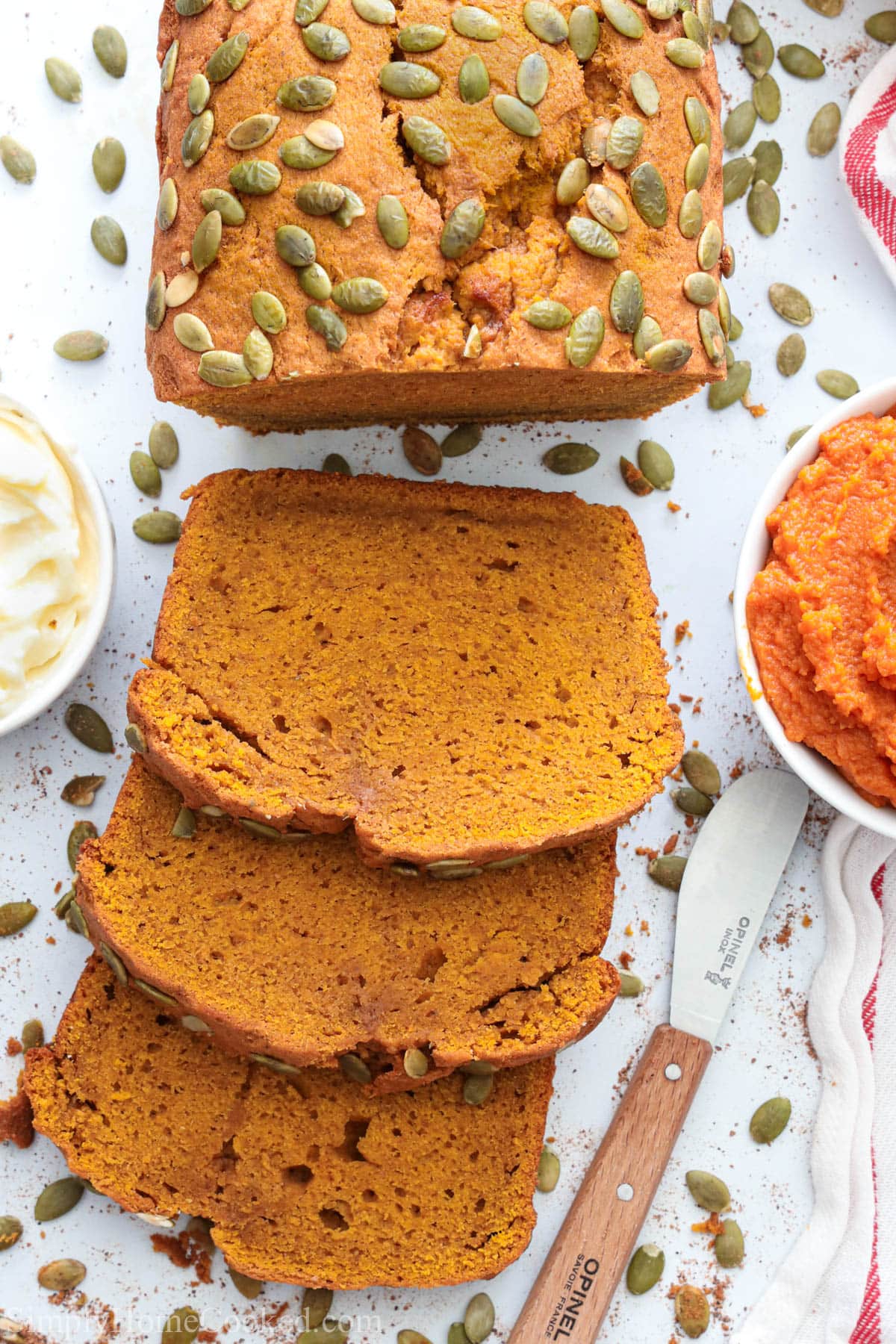 Vertical image of Pumpkin Bread, sliced and near butter and pumpkin puree