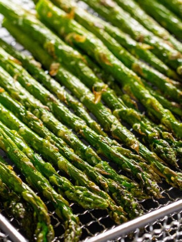 Vertical image of Air Fryer Asparagus lined up in a pan