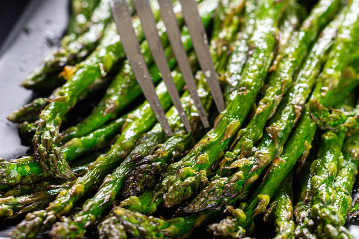 Horizontal image of Air Fryer Asparagus on a plate with a fork