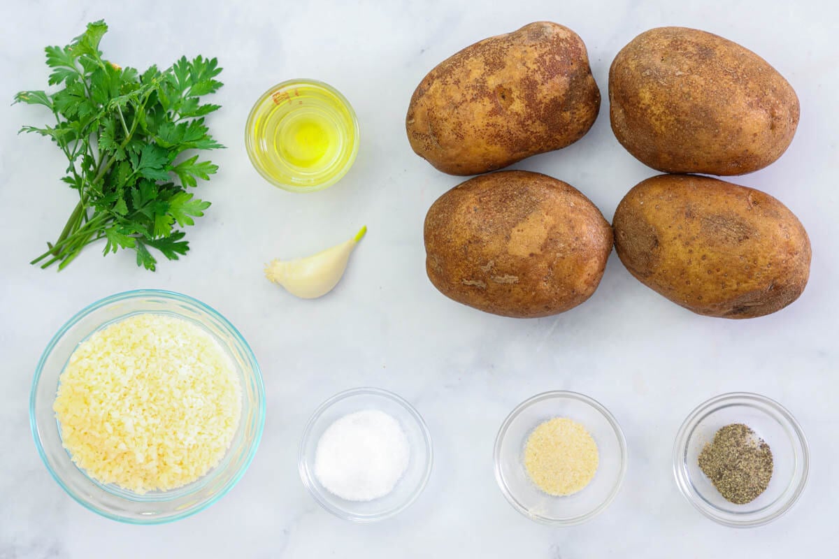 Ingredients to make Air Fryer Potato Wedges, including potatoes, garlic, oil, Parmesan cheese, salt, pepper, onion powder, and parsley