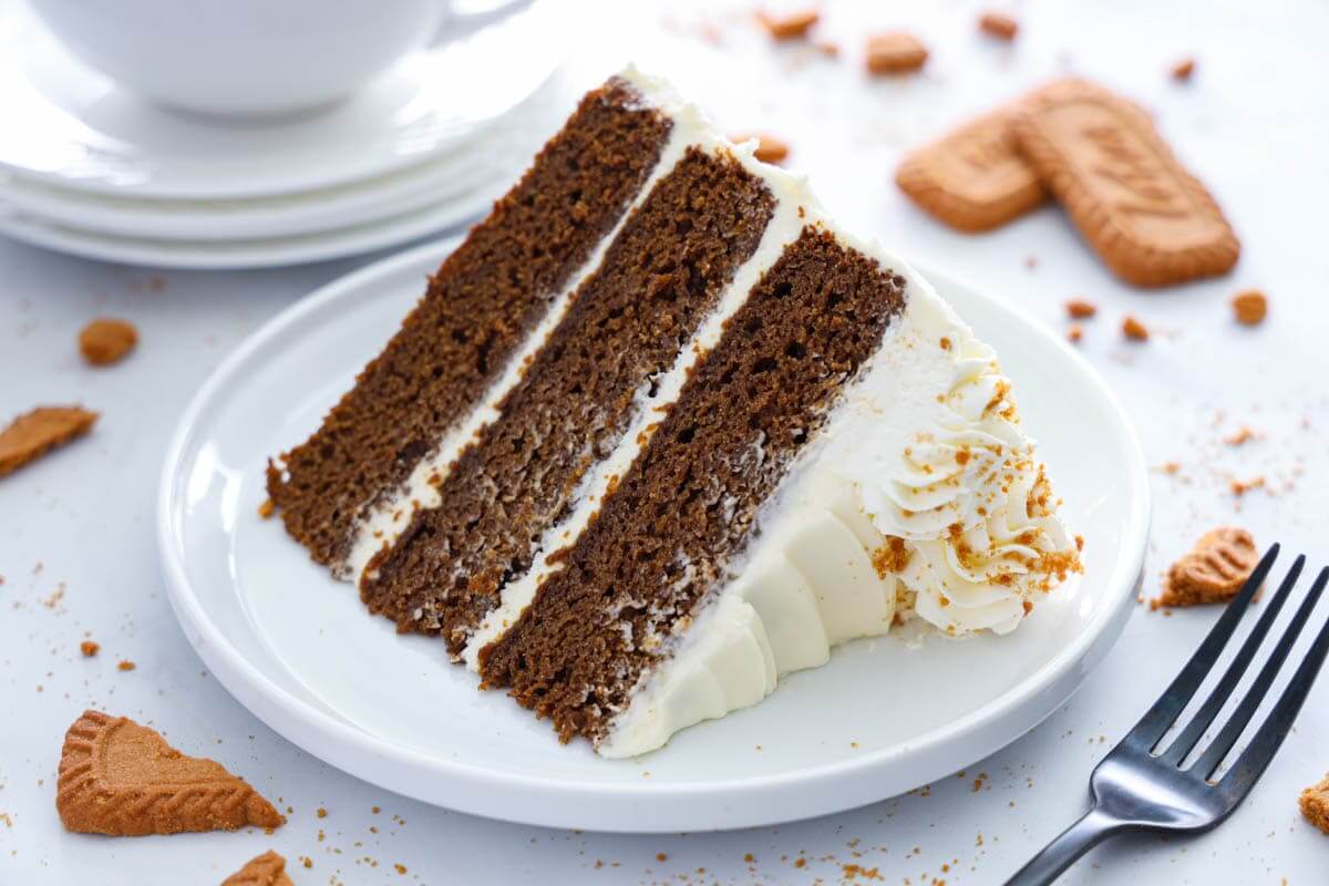 Horizontal image of a slice of Gingerbread Cake on a white plate with a fork nearby