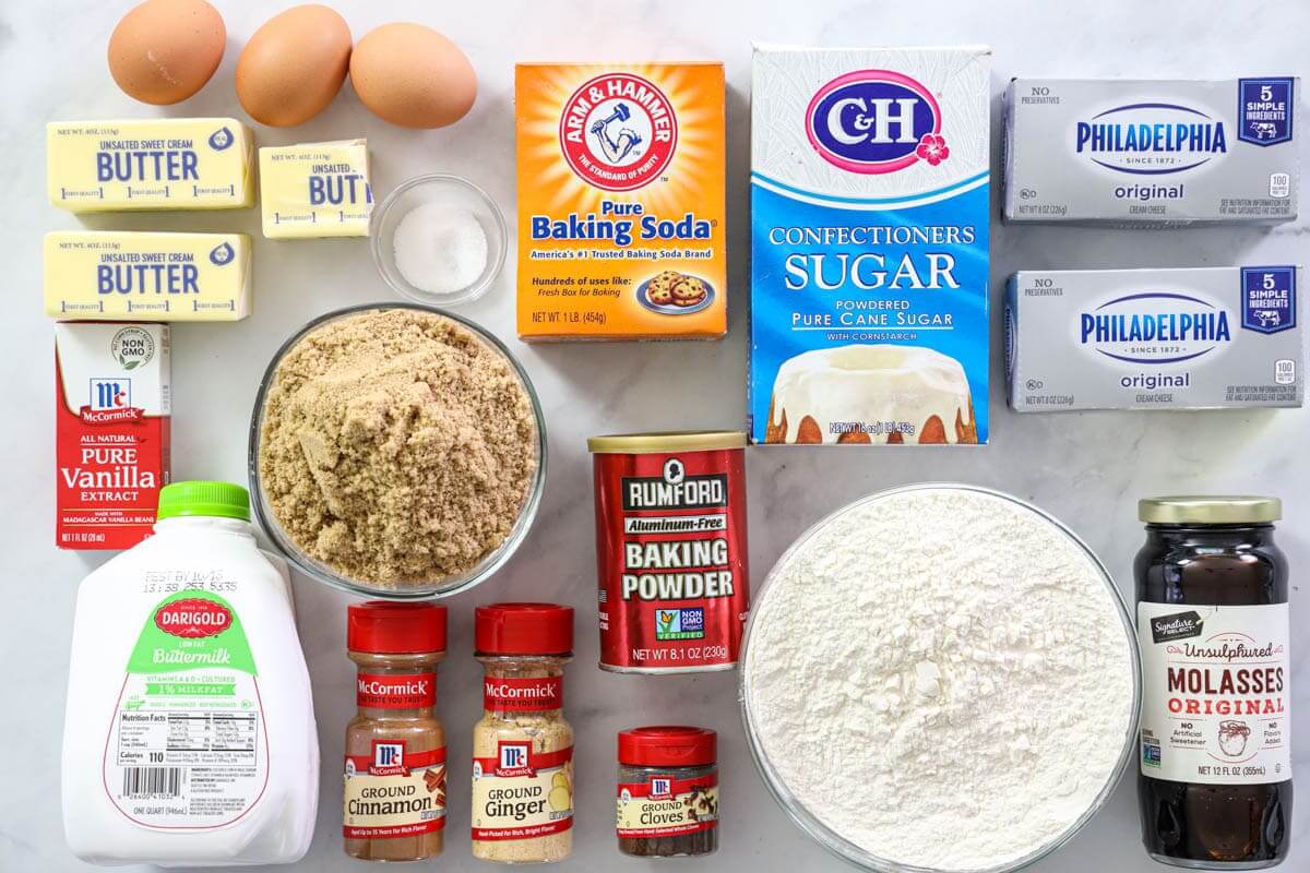 Ingredients for Gingerbread Cake, including eggs, butter, flour, baking soda, baking powder, salt, ground ginger, cinnamon, and cloves, molasses, buttermilk, powdered sugar, brown sugar, cream cheese, and vanilla extract.