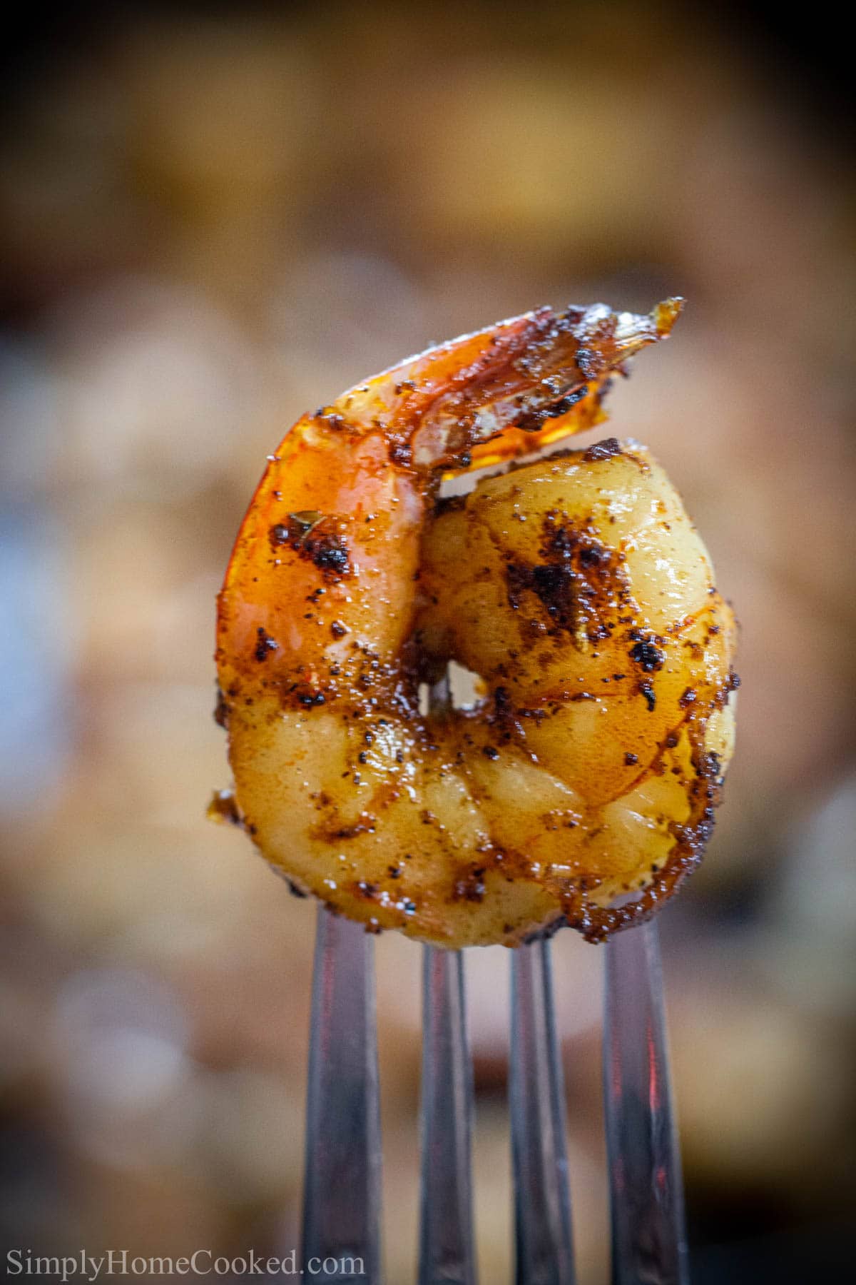 Vertical image of a close up of Cajun Shrimp on a fork