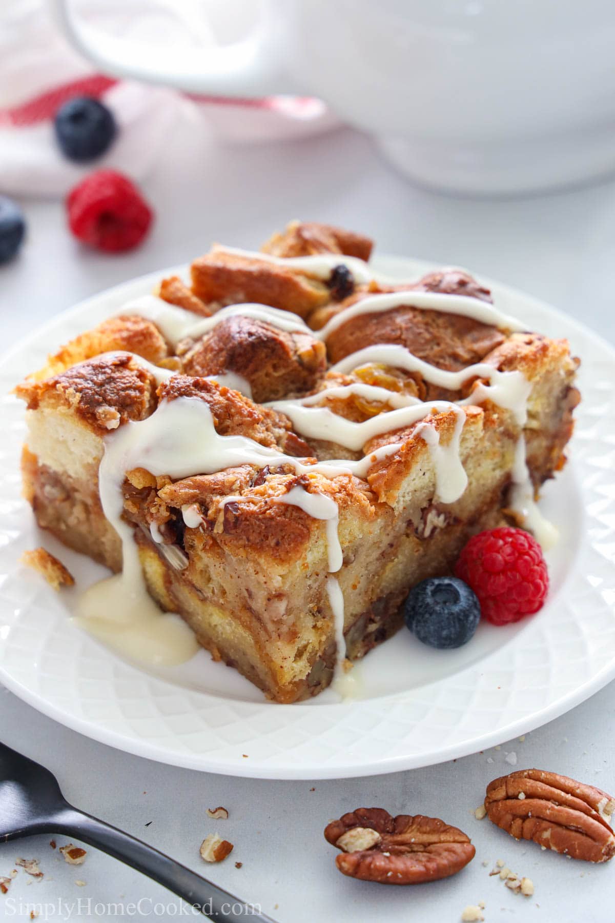 a slice of Bread Pudding covered in vanilla rum sauce on a plate with berries.