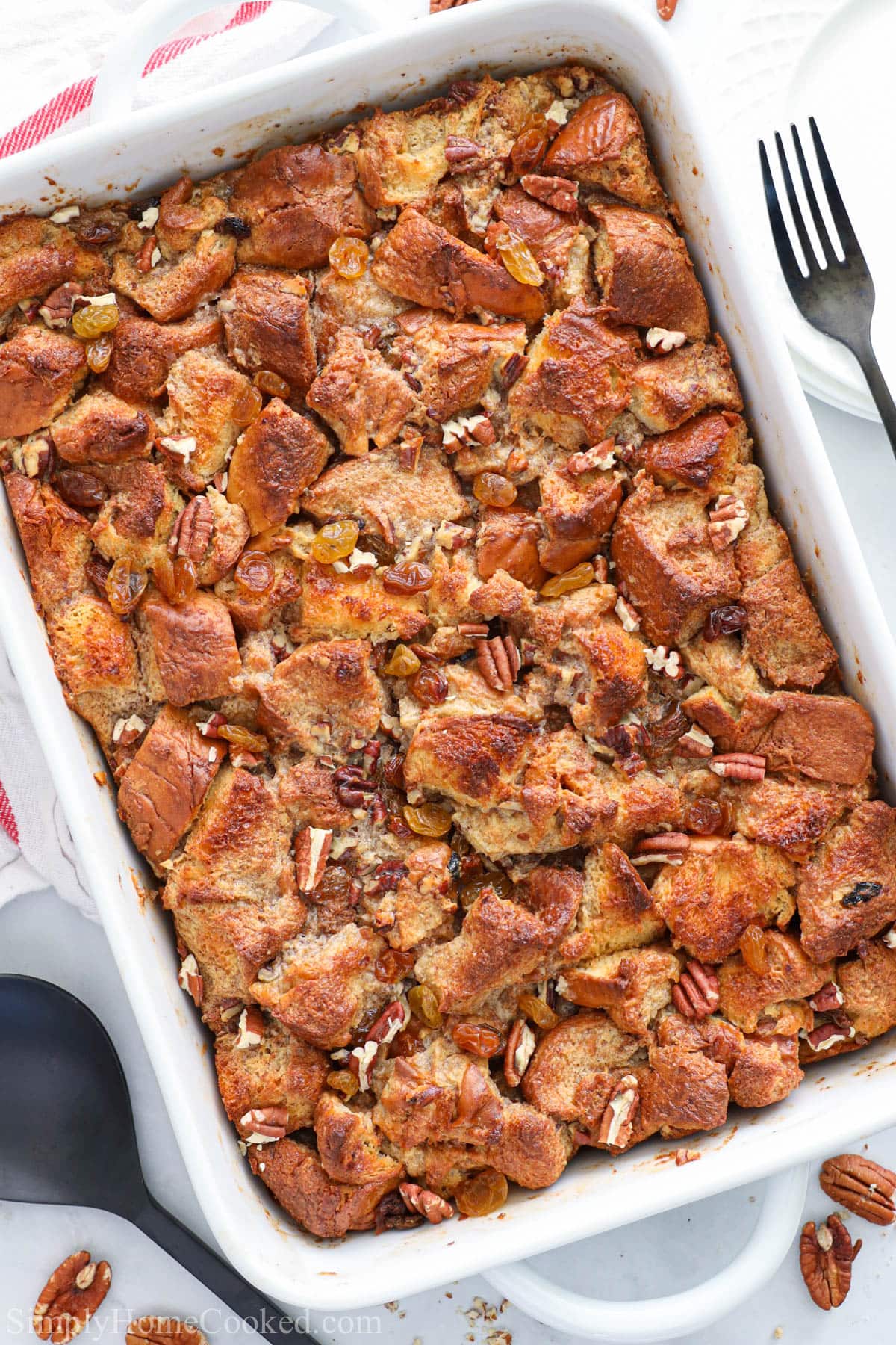 Vertical image of Bread Pudding in a baking dish with a fork nearby.