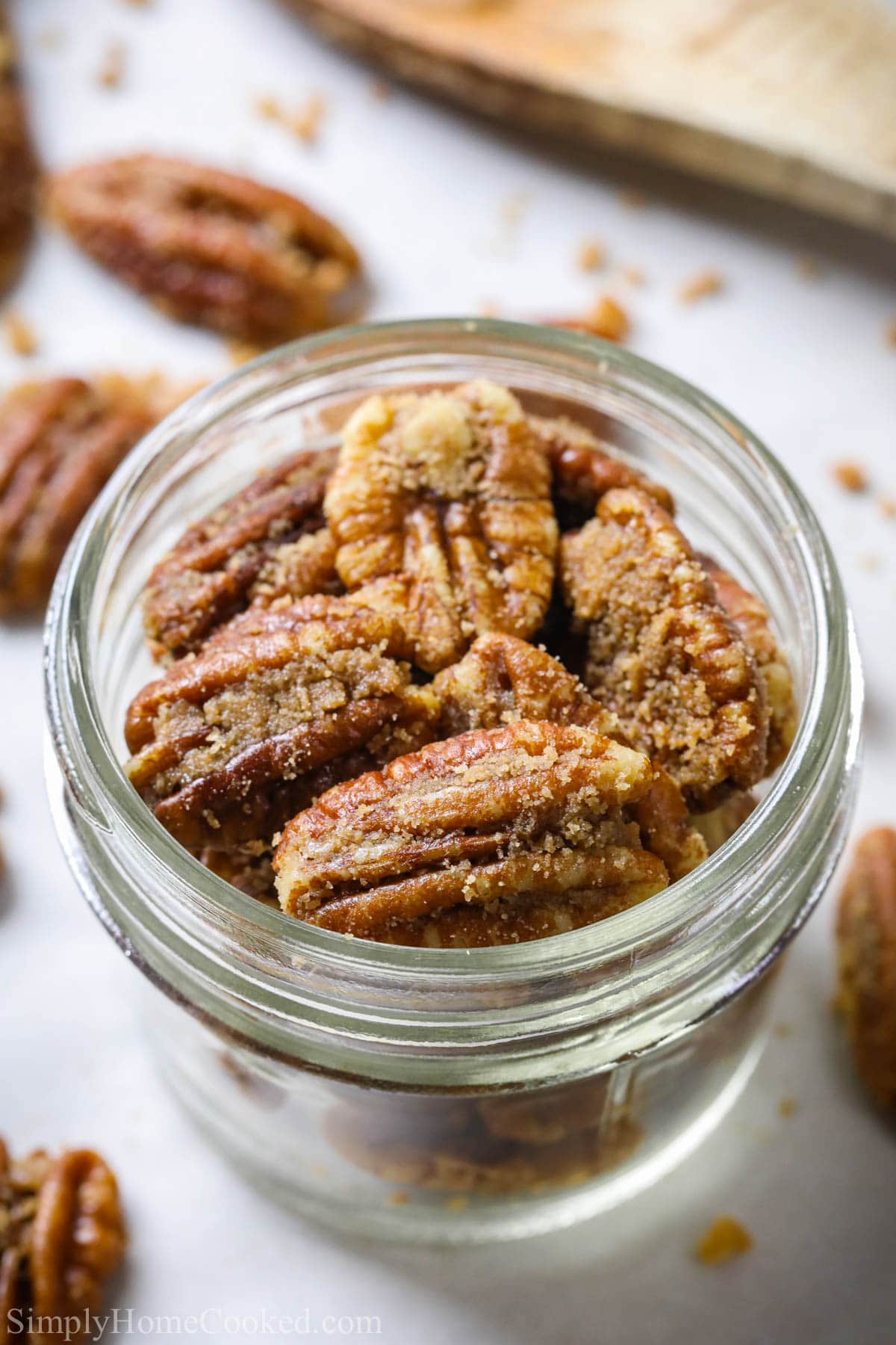 Vertical image of an overview of Candied Pecans in a mason jar.
