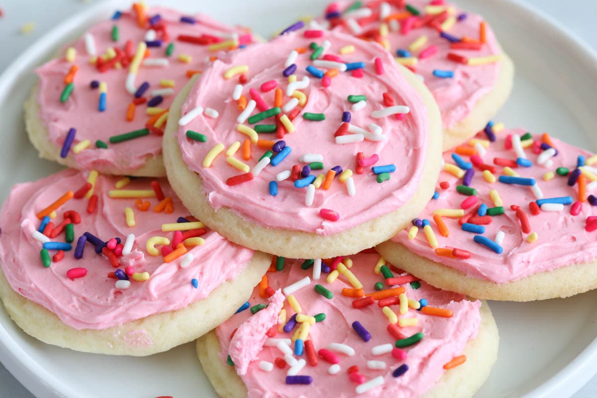close up image of frosted pink sugar cookies on a white plate