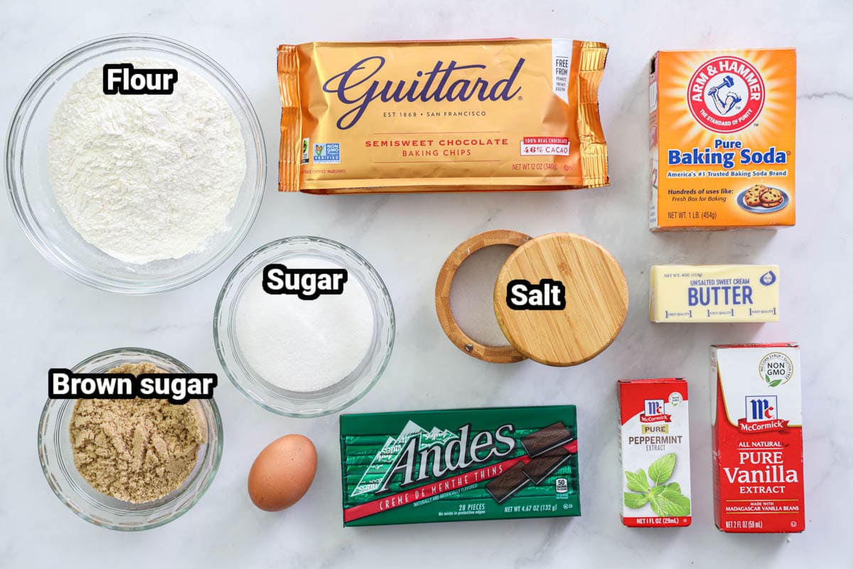 Ingredients for Mint Chocolate Chip Cookies, including flour, baking soda, salt, egg, brown sugar, granulated sugar, Andes candies, chocolate chips, peppermint and vanilla extract, and butter.
