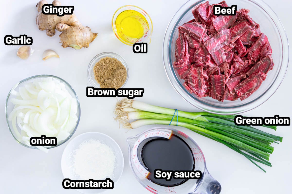 Ingredients for Mongolian Beef, including garlic, ginger, beef, oil, brown sugar, onion, green onion, soy sauce, and cornstarch.