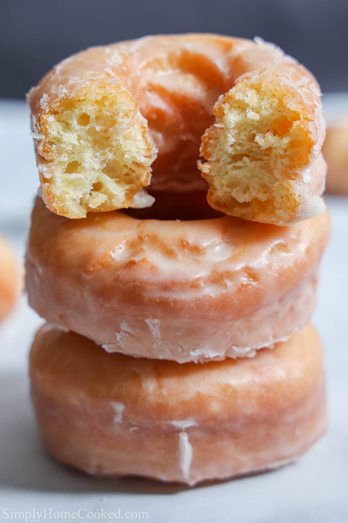 Old Fashioned Sour Cream Donuts in a stack with the top one missing a bite.