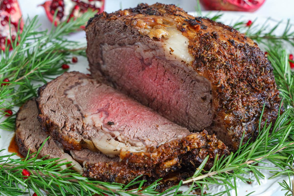 Prime Rib sliced on a plate with herbs and pomegranate seeds