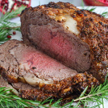 Prime Rib sliced on a plate with herbs and pomegranate seeds