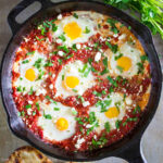 Vertical image of Shakshuka in a cast iron pan topped with feta cheese and cilantro.
