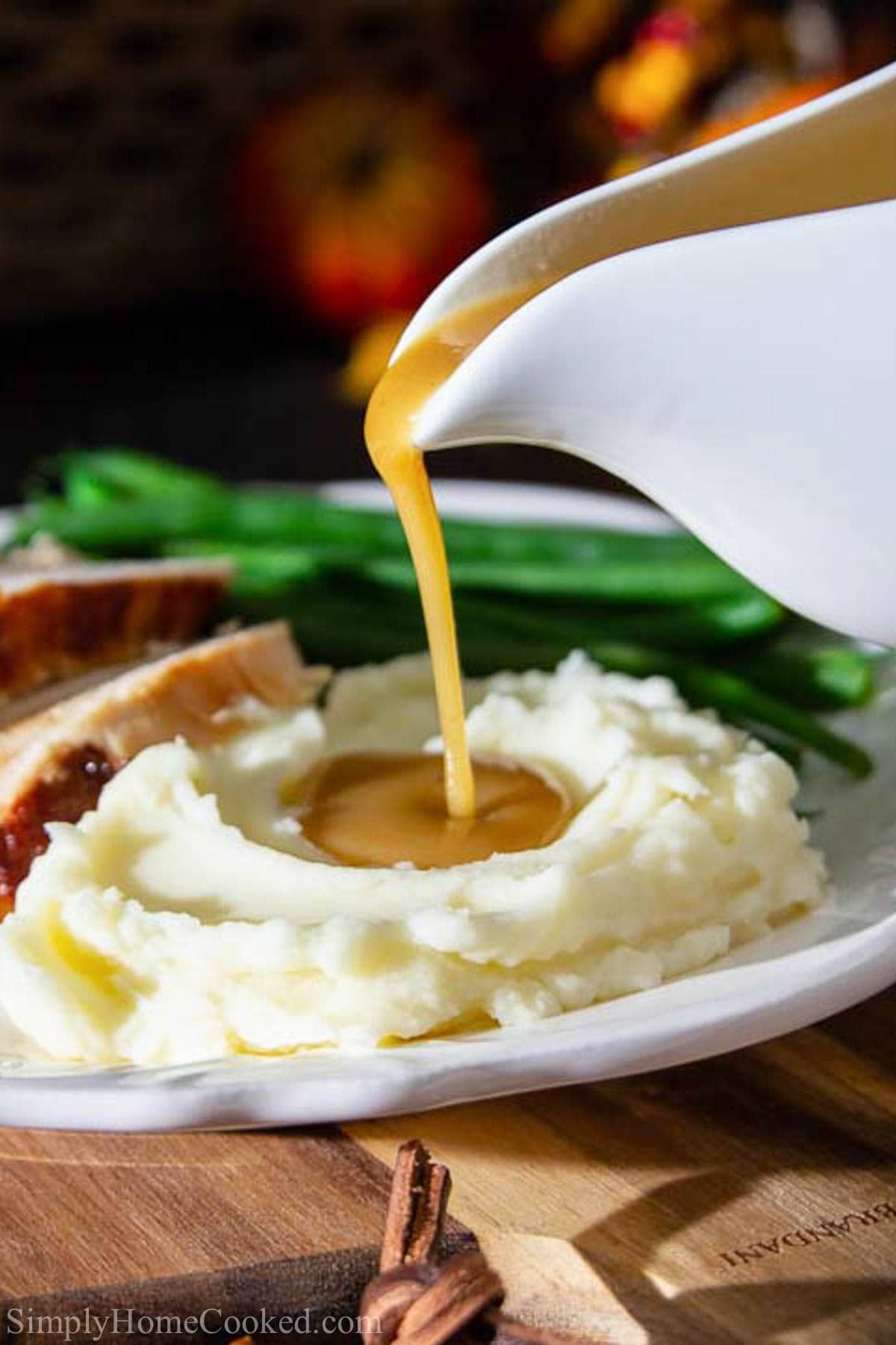 Vertical image of Turkey Gravy being drizzled on to mashed potatoes