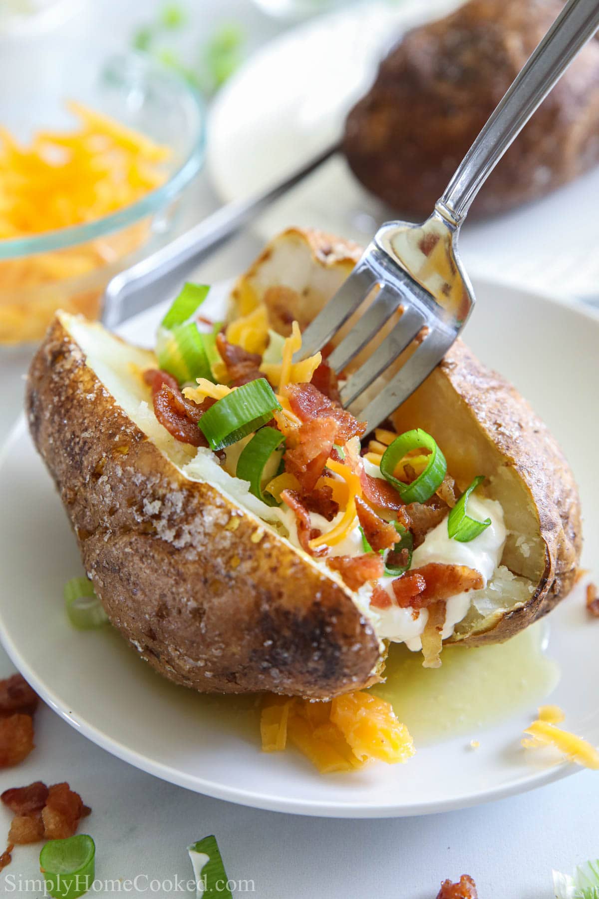Air Fryer Baked Potato with toppings on a plate and a fork digging in