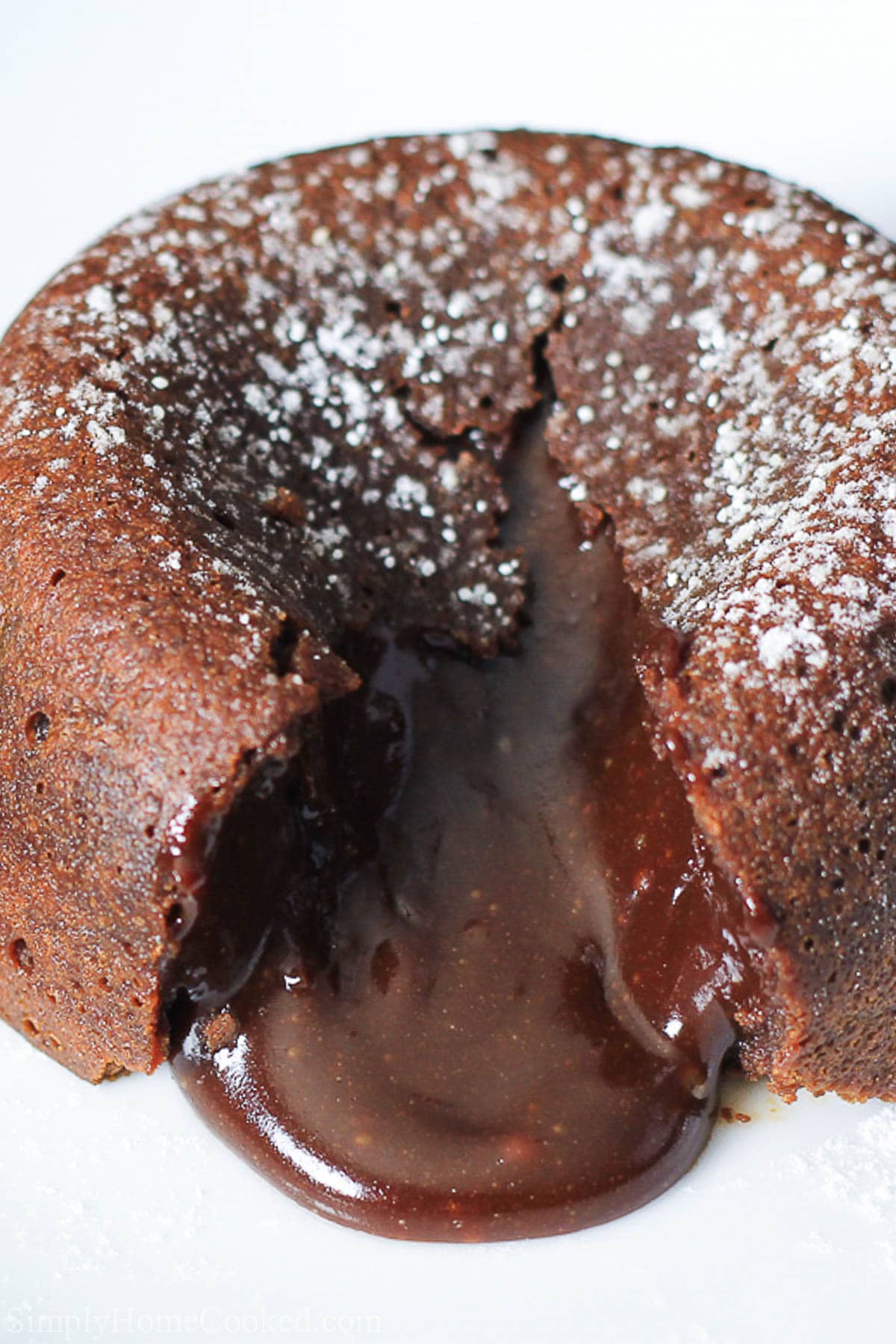 Vertical close up image of a split open Chocolate Lava Cake with powdered sugar on top 