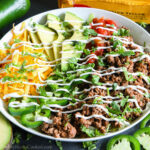 taco salad in a while bowl with sour cream drizzled on top