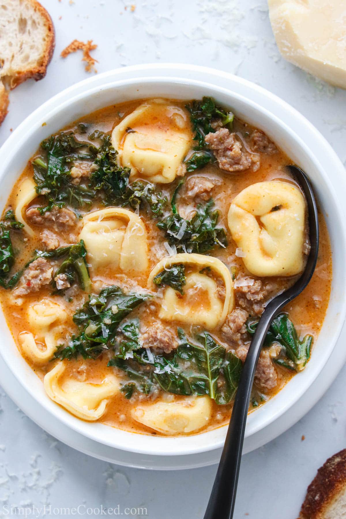 Vertical image of a bowl of Tortellini Soup with a spoon