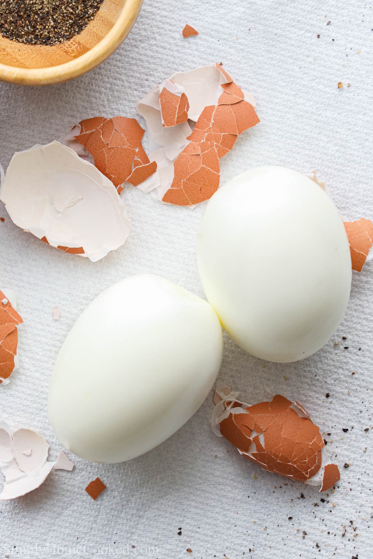 Vertical image of Air Fryer Hard Boiled Eggs peeled with the brown shells nearby