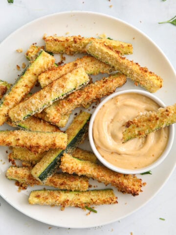 Air Fryer Zucchini Fries on a white plate with a dipping sauce in a ramekin