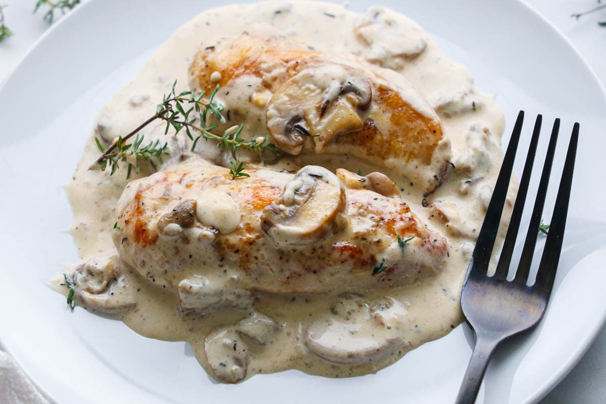 Horizontal image of Cream of Mushroom Chicken on a white plate with a fork.