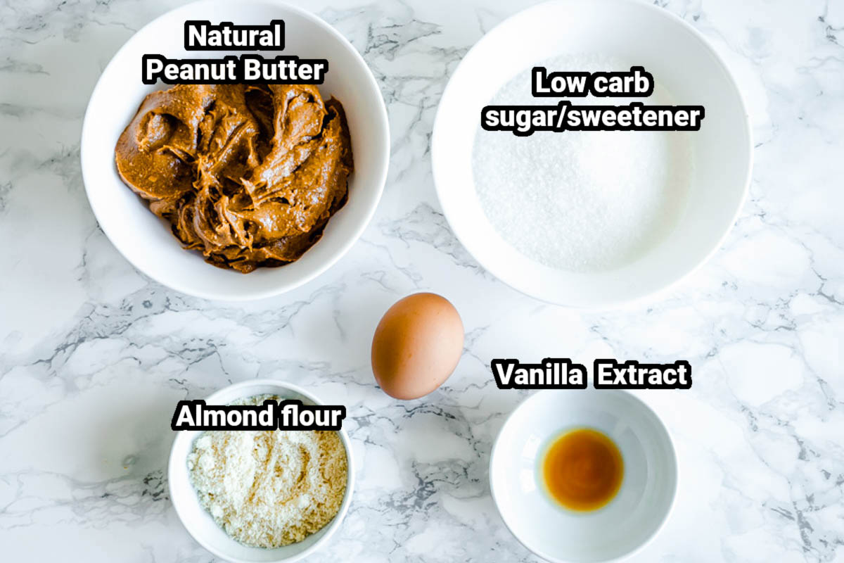 Ingredients for keto peanut butter cookies, including peanut butter, egg, low-carb sweetener, almond flour, and vanilla.