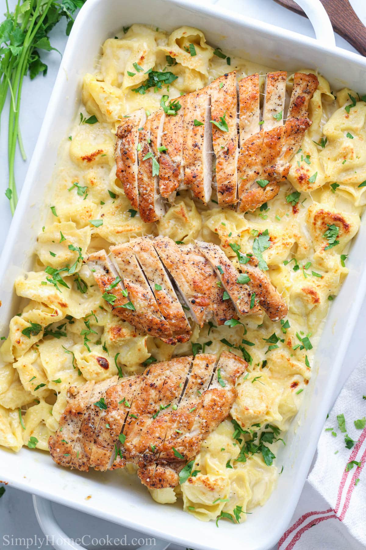 Asiago Tortelloni Alfredo with Grilled Chicken in a baking dish with parsley sprinkled on top