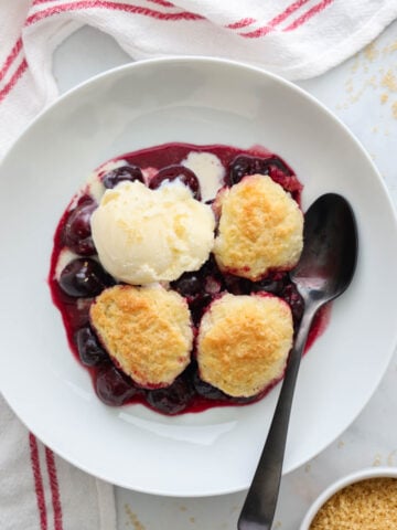 Savory Cherry Cobbler served on a white plate, topped with a scoop of ice cream.
