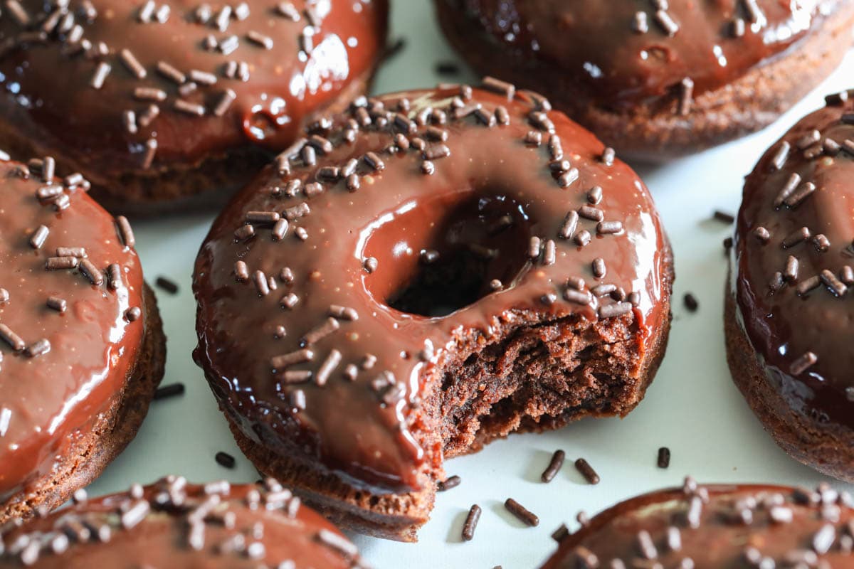 Chocolate Donuts covered in sprinkles, close up of one missing a bite