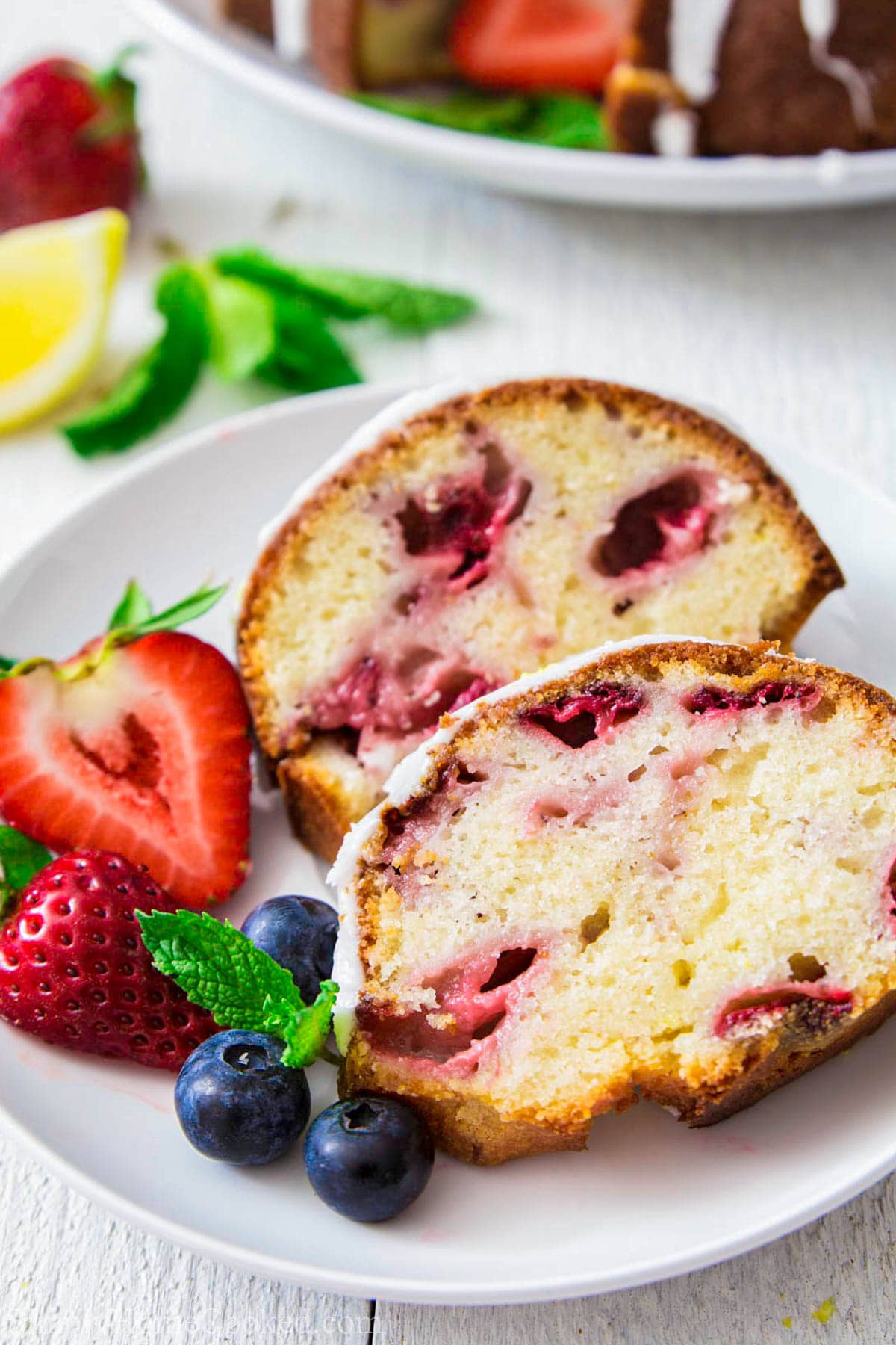 Slices of Strawberry Bundt Cake on a white plate with fresh berries