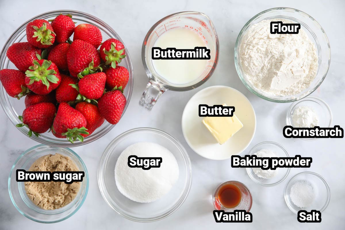 Ingredients for Strawberry Cobbler, including fresh strawberries, buttermilk, flour, butter, sugar, brown sugar, baking powder, cornstarch, vanilla, and salt.