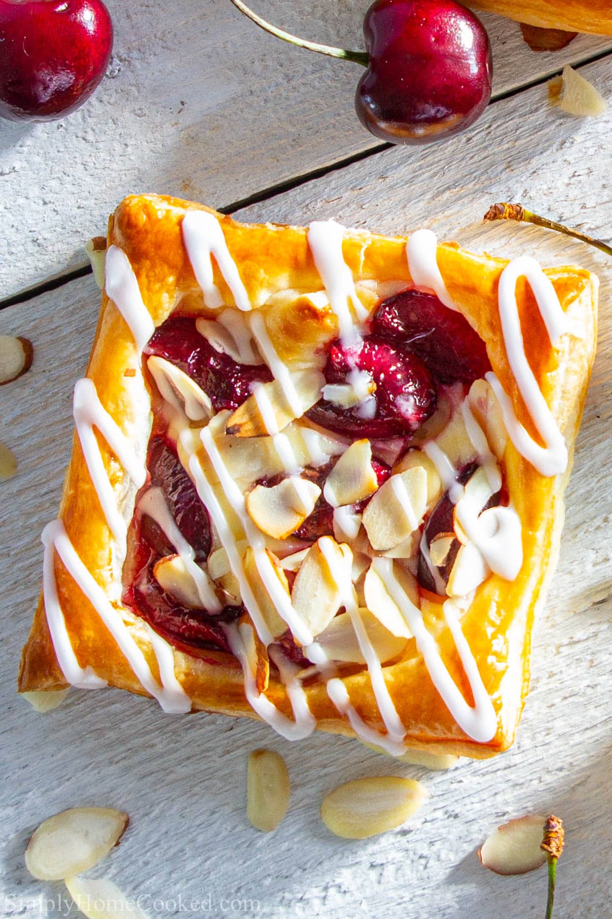 Cherry Danish surrounded by almonds and cherries.