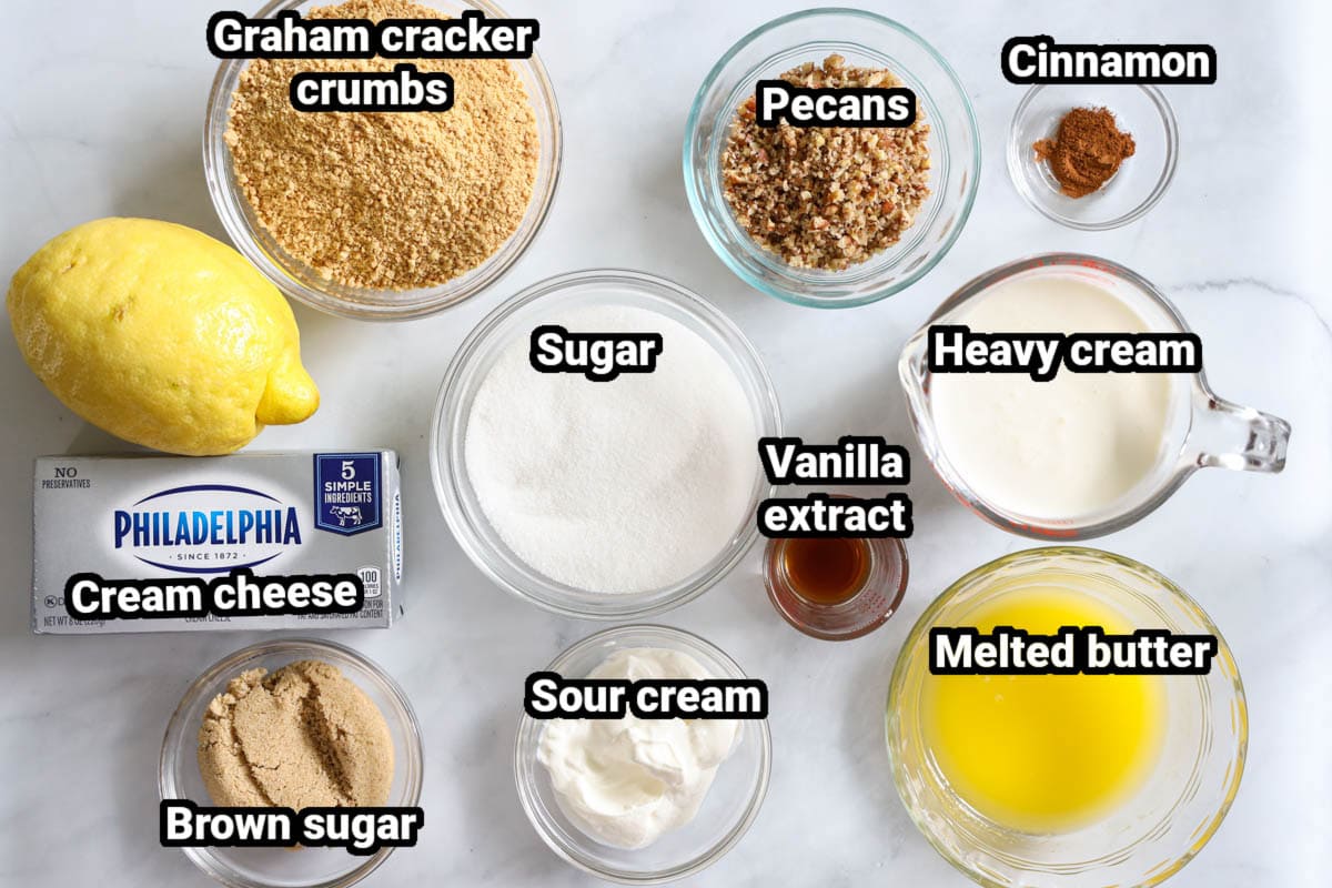 Ingredients for No Bake Mini Cheesecakes, including graham crackers, pecans, butter, cinnamon, sugar, heavy cream, lemon cream cheese, sour cream, and vanilla.