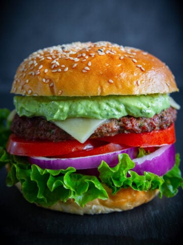 Spicy Chipotle Burgers with Avocado Sauce with lettuce, tomato, cheese, and onion on a bun.
