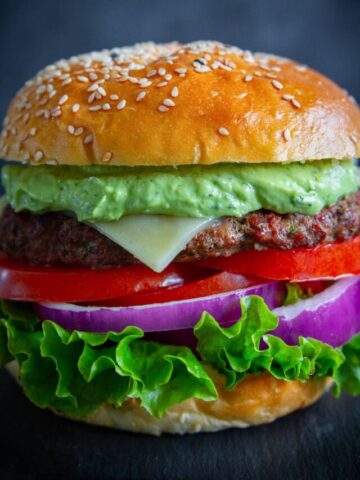 Spicy Chipotle Burgers with Avocado Sauce with lettuce, tomato, cheese, and onion on a bun.