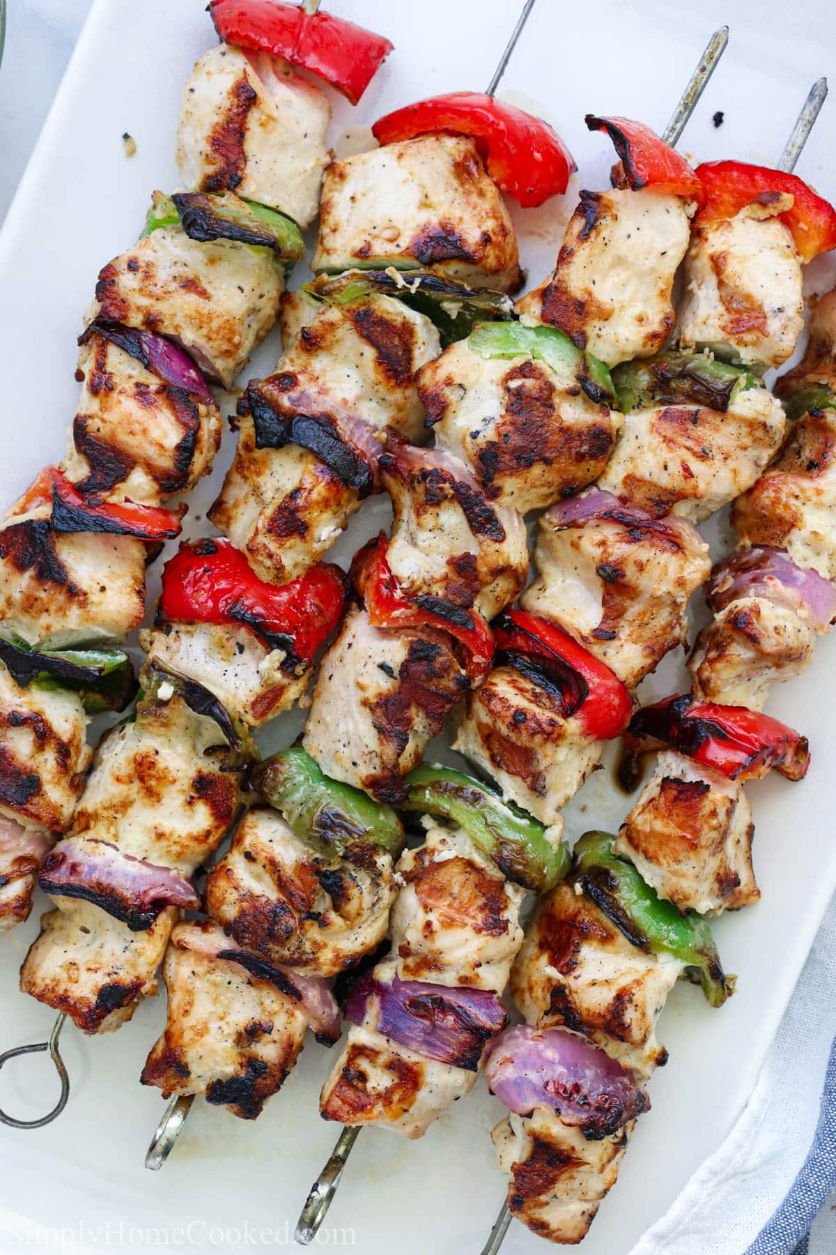 Grilled chicken kabobs with red onion and green and red pepper pieces on metal skewers