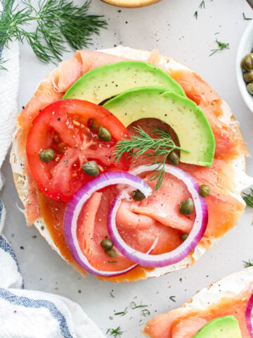 Smoked Salmon Bagel topped with onion, capers, tomato, dill, and avocado.